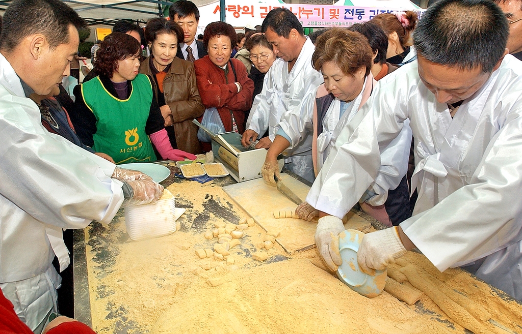 대전의 한 장터에서 시민들이 인절미 만드는 모습을 지켜보고 있다. 2003년[연합뉴스 자료사진]