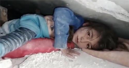 7일(현지시간) 무너진 건물 잔해에서 동생을 보호하는 한 소녀 