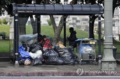 캘리포니아 LA의 한 버스 정류장에서 비를 피하는 노숙자