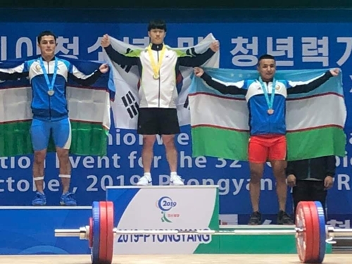 Esta foto, proporcionada por la Federación de Halterofilia de Corea del Sur, muestra al surcoreano Park Hyeong-o sosteniendo la bandera nacional después de ganar el oro en arrancada masculina de menores de 17 años de 73 kilogramos como parte del Campeonato de Halterofilia Júnior y Juvenil de Asia 2019 en Pyongyang.