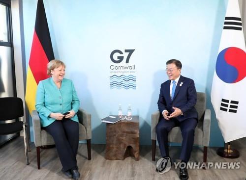 El presidente surcoreano, Moon Jae-in, dialoga con la canciller alemana, Angela Merkel, el 12 de junio de 2021, durante su reunión en Cornualles, en el Reino unido.