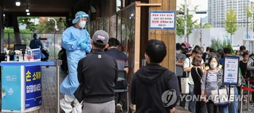 Un trabajador sanitario observa a las personas que esperan en fila para someterse a las pruebas del nuevo coronavirus, el 27 de septiembre de 2021, en una clínica provisional, en el distrito de Songpa, en Seúl.