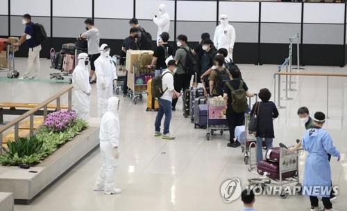 La foto de archivo, tomada el 13 de julio de 2021, muestra a residentes y diplomáticos surcoreanos procedentes de la India siendo orientados por los funcionarios de prevención epidemiológica, tras su llegada al Aeropuerto Internacional de Incheon, al oeste de Seúl, en medio de la cuarta ola del COVID-19.