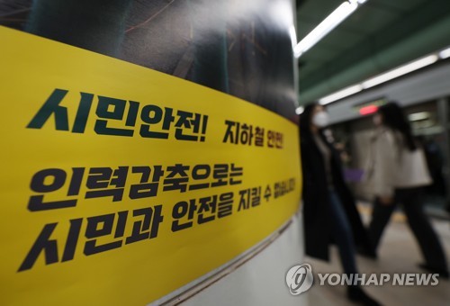 Las personas pasan frente a un cartel del sindicato de trabajadores de Seoul Metro -el operador del metro de Seúl- en la estación Gwanghwamun, el 29 de noviembre de 2022, en el centro de la capital, que destaca sobre la seguridad de las personas y del metro, afirmando que no se puede garantizar la seguridad del pueblo con una reducción de la fuerza laboral.