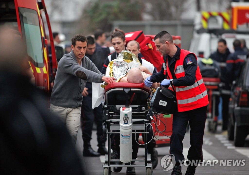 7일(현지시간) 프랑스 파리에서 발생한 주간지 테러 사건 현장에서 구급요원들이 부상자를 옮기고 있다. (AP 연합뉴스) 