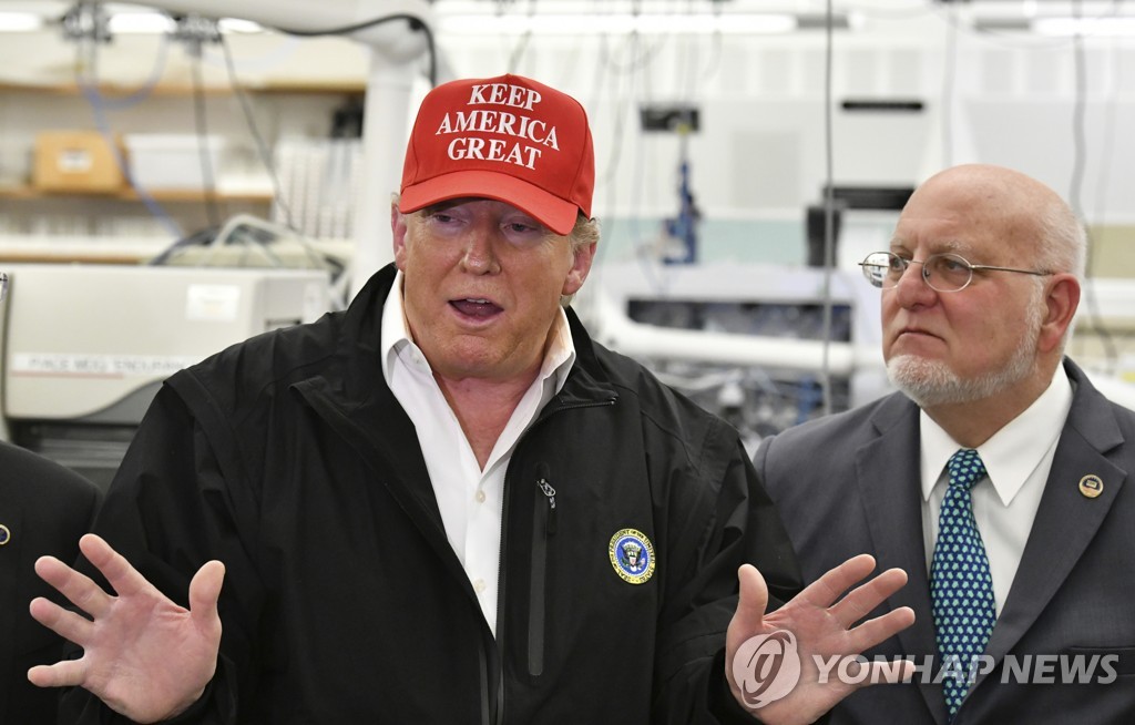This photo by the Atlanta Journal-Constitution, published via the Associated Press, shows U.S. President Donald Trump speaking to members of the press as Robert Redfield, director of the Centers for Disease Control and Prevention, looks on at the agency's headquarters in Atlanta, Georgia, on March 6, 2020. (Yonhap)