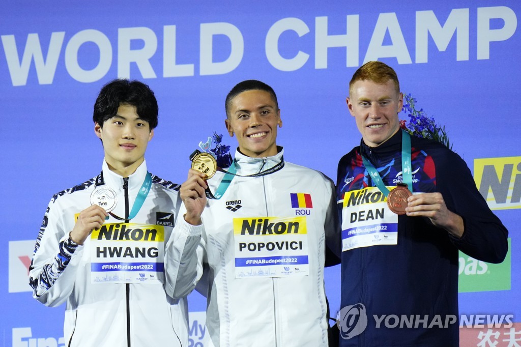 In this Associated Press photo, Hwang Sun-woo of South Korea (L) poses with his silver medal from the men's 200m freestyle at the FINA World Championships at Duna Arena in Budapest on June 20, 2022. Hwang stands next to gold medalist, David Popovici of Romania (C), and bronze medalist, Tom Dean of Britain. (Yonhap)