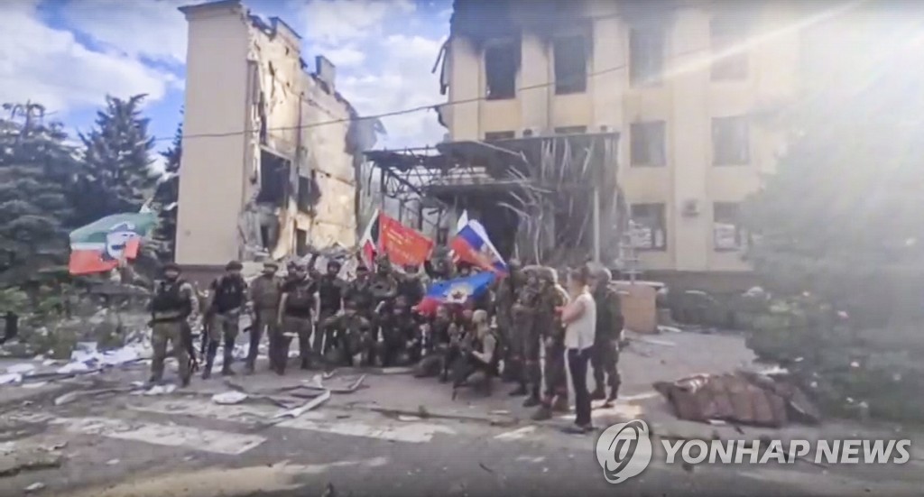 파괴된 리시찬스크 건물 앞서 기념촬영하는 러시아군 병사들