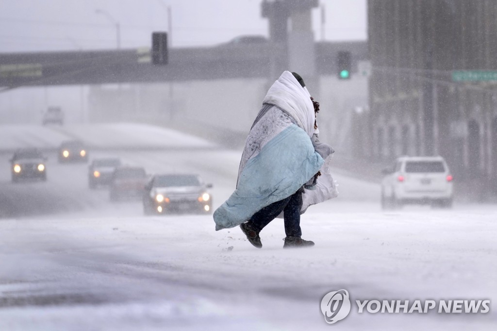 미국 세인트루이스에서 눈이 내리는 가운데 담요를 두르고 길을 건너는 한 시민