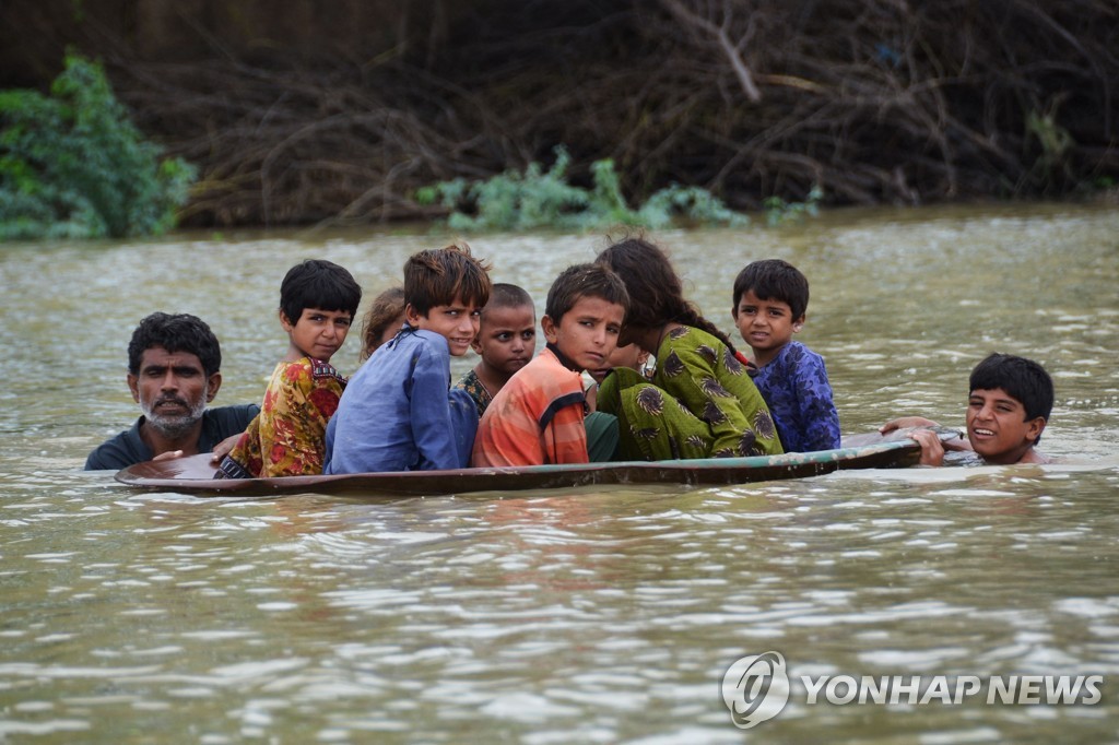 파키스탄 홍수 속 위성안테나 접시를 뗏목으로 타고있는 아이들