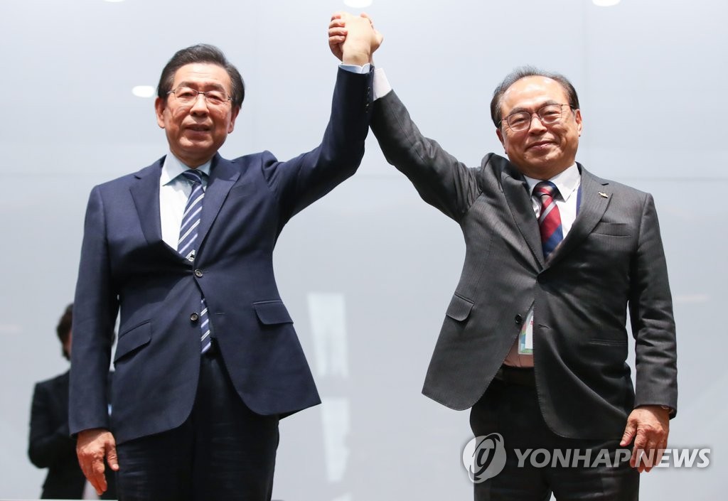 Seoul Mayor Park Won-soon (L) and Busan Mayor Oh Keo-don raise their arms at the Jincheon National Training Center in Jincheon, 90 kilometers south of Seoul, on Feb. 11, 2019, after Seoul defeated Busan to become the South Korean candidate city for a joint bid to host the 2032 Summer Olympics with North Korea. (Yonha)