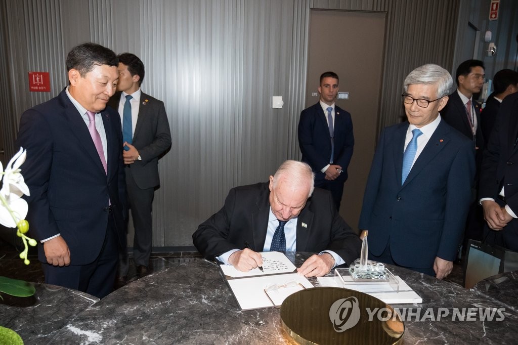 Israeli President Reuven Rivlin signs a visitors' book during a tour of Lotte World Tower in eastern Seoul on July 14, 2019, in this photo provided by Lotte. (PHOTO NOT FOR SALE) (Yonhap)