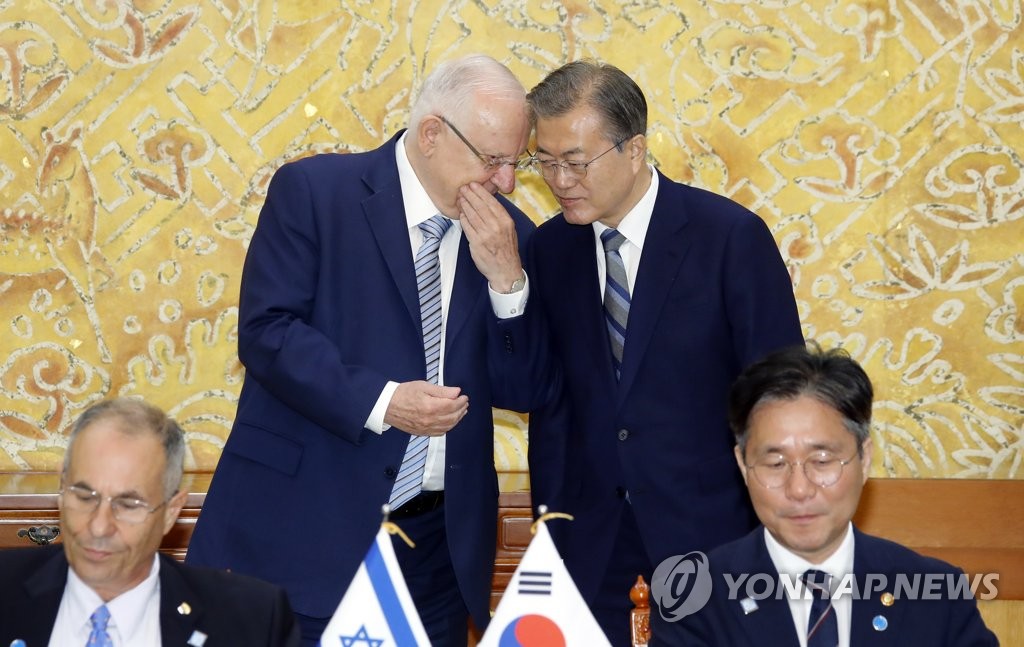 Israeli President Reuven Rivlin (back row, L) whispers to South Korean President Moon Jae-in (back row, R), as Industry Minister Sung Yun-mo (front row, R) and Israel's Ambassador to Seoul Chaim Choshen sign a memorandum of understanding on promoting hydrogen economy partnerships at Cheong Wa Dae in Seoul on July 15, 2019. (Yonhap)