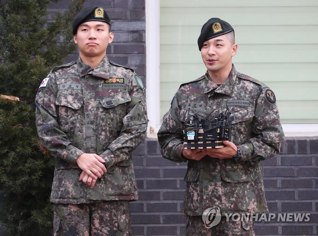 11月10日，在京畿道龙仁市地面作战司令部前，BIGBANG成员太阳（右）和大成答记者问。当天，二人正式退伍。 韩联社