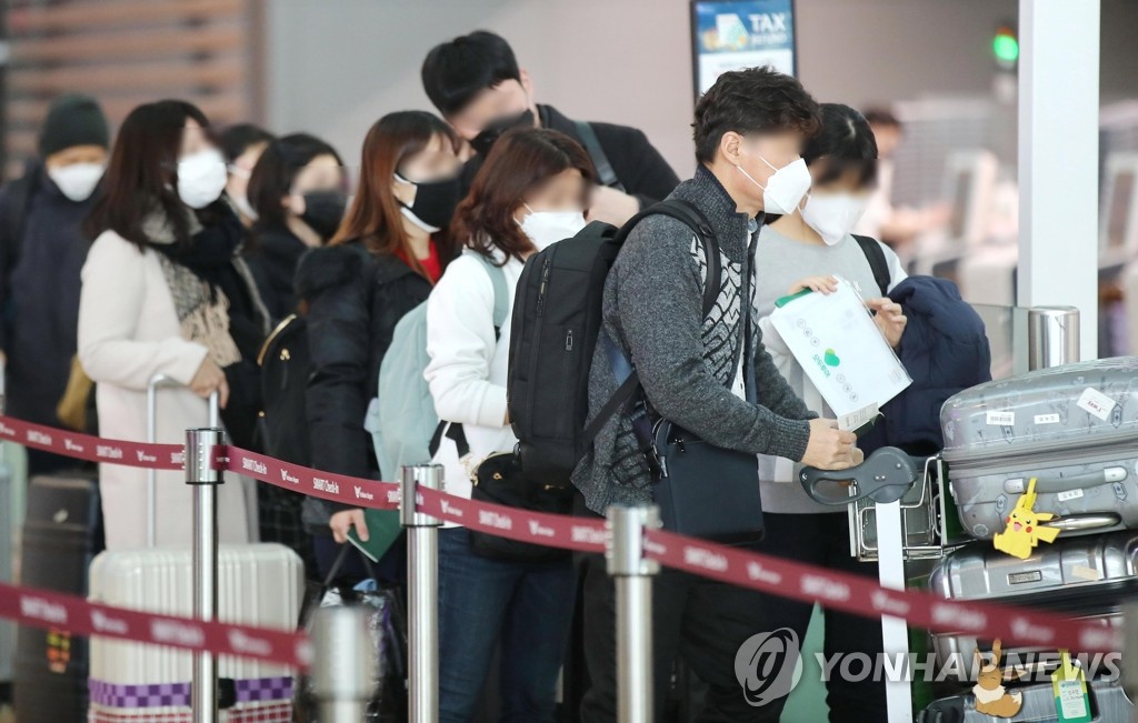 This photo taken on Feb. 7, 2020, shows outbound passengers wearing masks waiting in a queue to undergo departure procedures at Incheon International Airport in Incheon, just west of Seoul. (Yonhap)