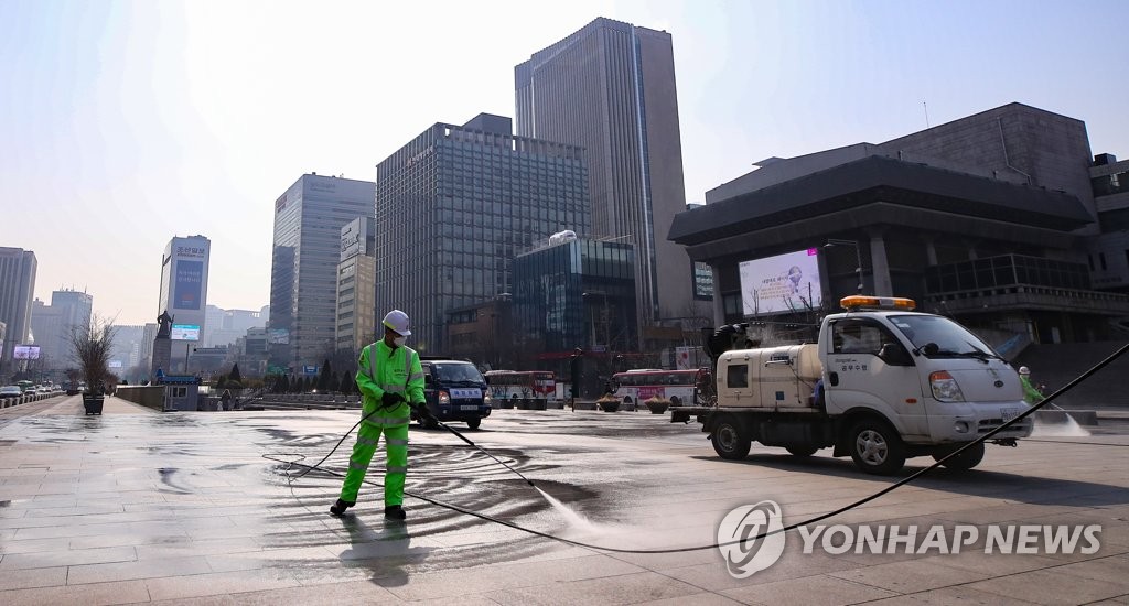 Officials from the Jongno Ward Office disinfect Gwanghwamun Square in central Seoul in an effort to contain the new coronavirus. (Yonhap)