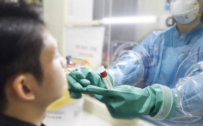 A nurse takes a sample from a man to test for the new coronavirus through a "glove wall" at Boramae Medical Center in Seoul, in this undated photo released by the hospital on March 16, 2020. The medical center has introduced the system, which separates a suspected patient and a medical worker when a COVID-19 virus test is conducted, for the first time in South Korea. (PHOTO NOT FOR SALE) (Yonhap)
