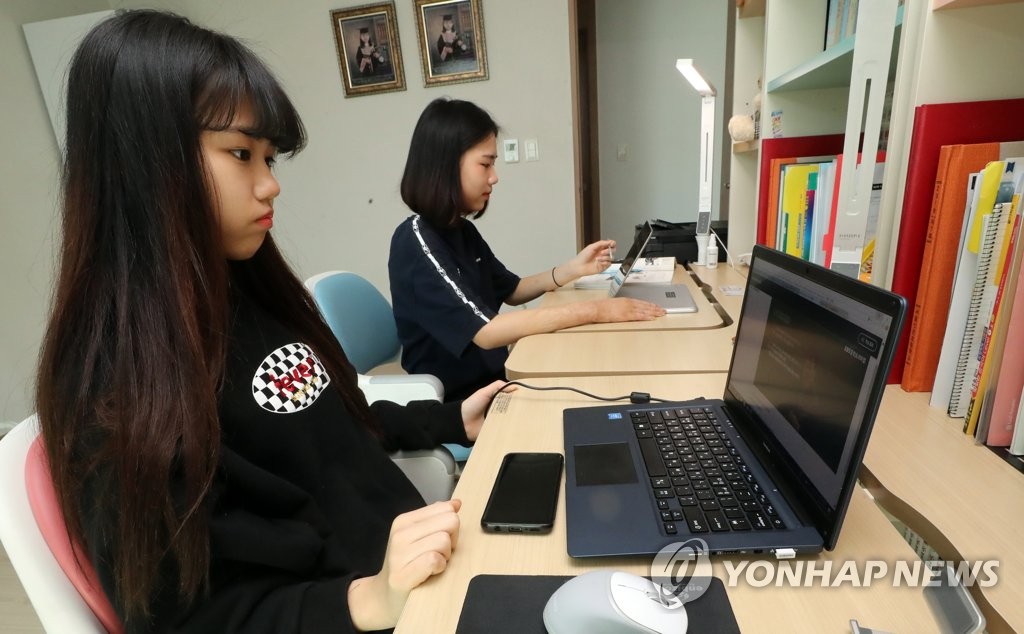 Twin sisters, both of whom are in grade three at middle schools, take online classes at home in Seoul on April 9, 2020, as South Korea began the new school year. (Yonhap)