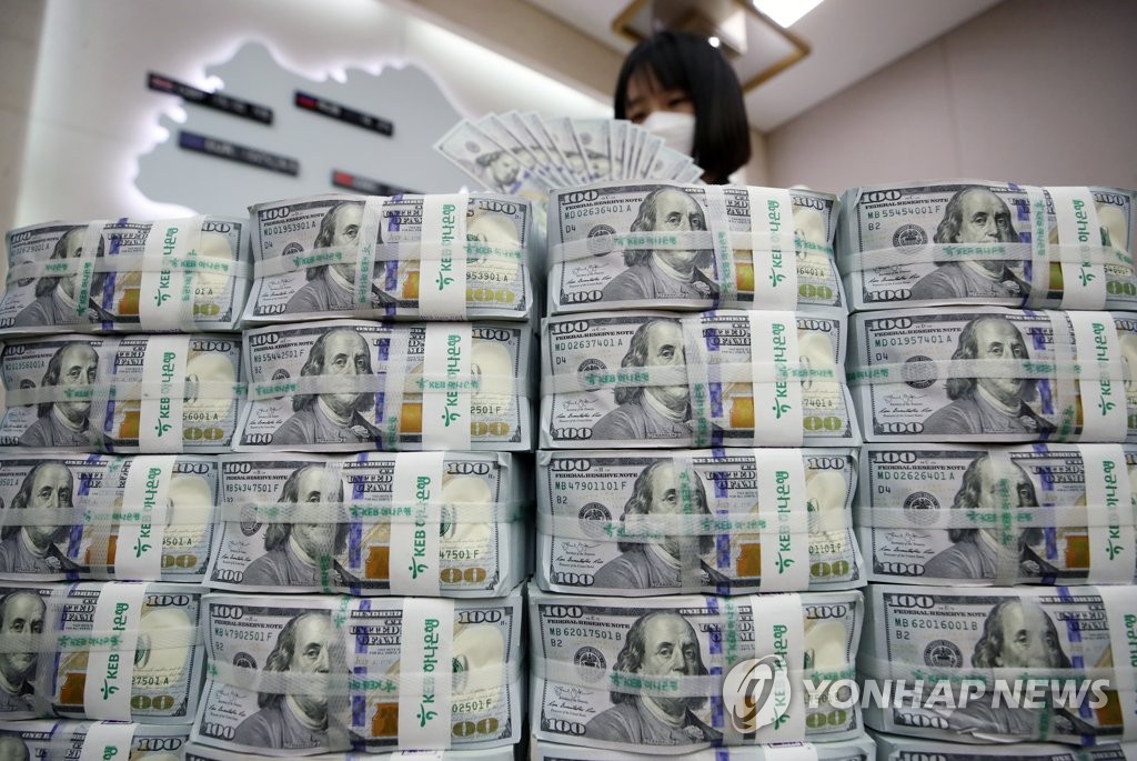 In this photo taken April 17, 2020, a bank official inspects U.S. currency at a branch office in Seoul. (Yonhap)