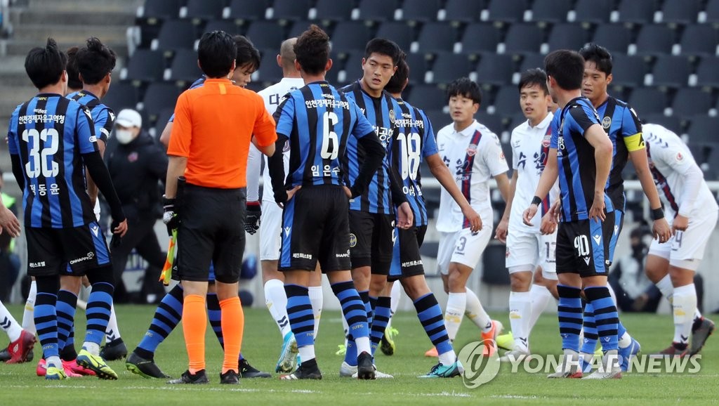 In this file photo from April 23, 2020, players from Incheon United (in blue) and Suwon FC acknowledge each other after a practice match at Incheon Football Stadium in Incheon, 40 kilometers west of Seoul. (Yonhap)