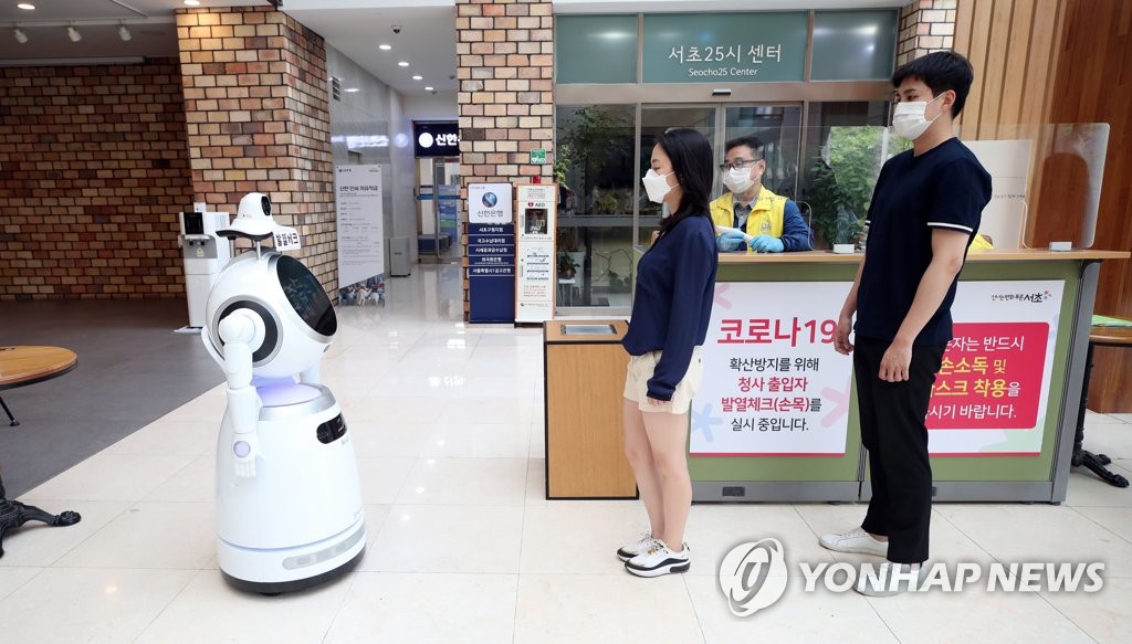 Visitors stand in a line to have their body temperatures checked by a robot at the Seocho district office in southern Seoul on June 4, 2020. (Yonhap)
