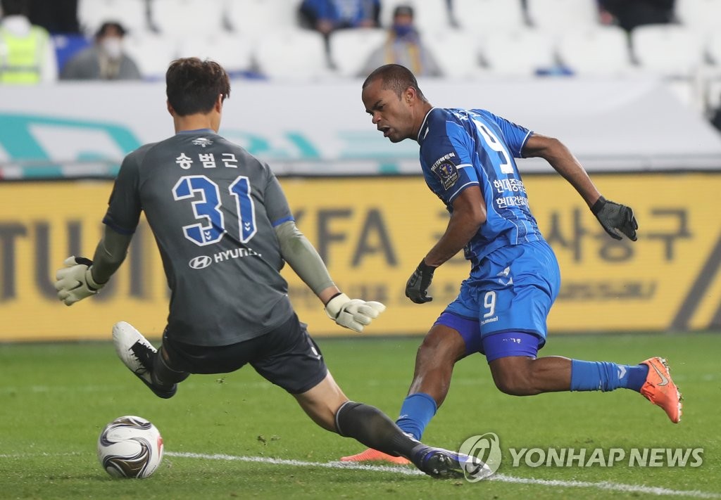 Junior Negrao of Ulsan Hyundai FC (R) scores past Jeonbuk Hyundai Motors goalkeeper Song Bum-keun during the first leg of the FA Cup final at Ulsan Munsu Football Stadium in Ulsan, 415 kilometers southeast of Seoul, on Nov. 4, 2020. (Yonhap)