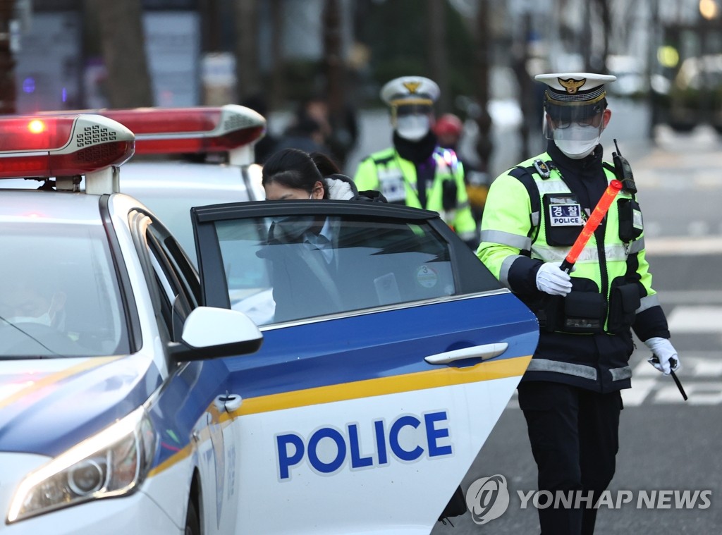A student taking the College Scholastic Ability Test gets into a police car to be escorted to her test center in Seoul on Dec. 3, 2020. (Yonhap)