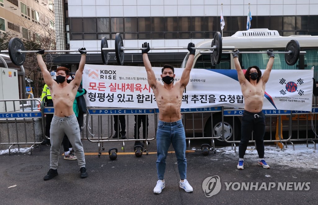 Health trainers demonstrate CrossFit exercises amid this year's strongest cold spell during a news conference in front of the main office of the ruling Democratic Party in Seoul on Jan, 8, 2021, to call for the government to take realistic steps in allowing the reopening of indoor sports facilities. (Yonhap)