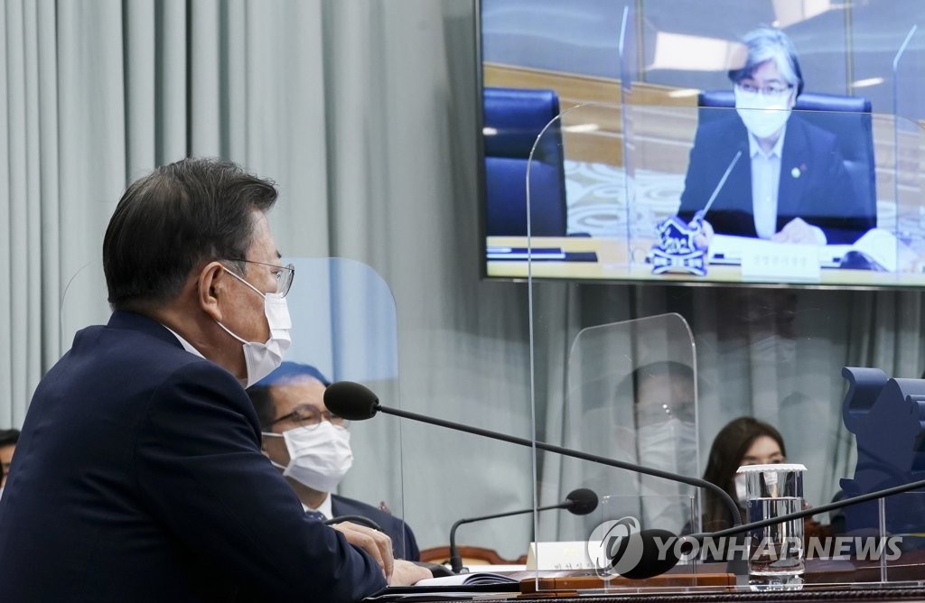 President Moon Jae-in (L) receives a policy briefing from Jeong Eun-kyeong (on screen), commissioner of the Korea Disease Control and Prevention Agency (KDCA), at Cheong Wa Dae in Seoul on Jan. 25, 2021. (Yonhap)
