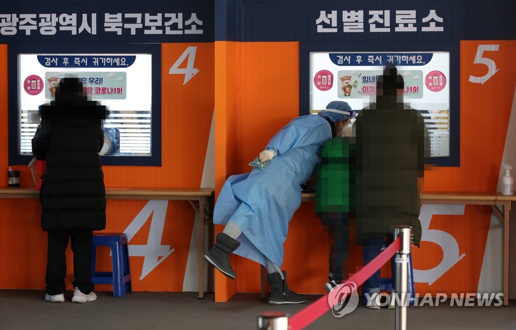 A medical worker helps people get a COVID-19 test in the southwestern city of Gwangju on Feb. 9, 2021. (Yonhap) 