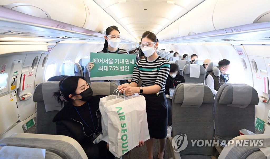 Une hôtesse de l'air vend des produits hors taxes à une passagère dans un vol vers nulle part de la compagnie aérienne à bas prix Air Seoul, le 21 février 2021. (Photo de pool)