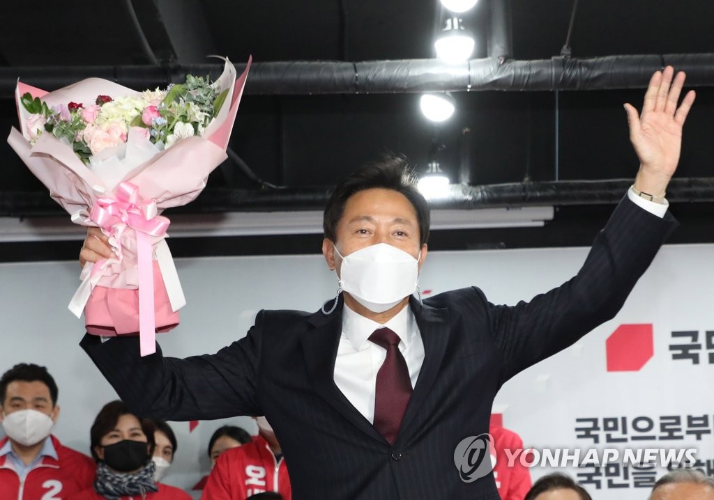 Oh Se-hoon, candidate of the main opposition People Power Party, raises his hands up with a bouquet of flowers in one hand at the party headquarters in Seoul on April 8, 2021 as early ballot count indicates his victory in the Seoul mayoral by-election. (Yonhap)