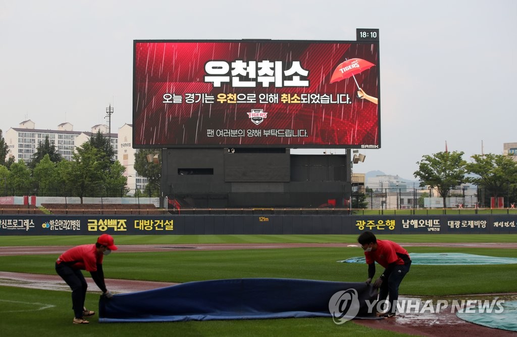 In this file photo from June 30, 2021, members of the grounds crew at Gwangju-Kia Champions Field in Gwangju, 330 kilometers south of Seoul, remove the tarp from the field after a Korea Baseball Organization regular season game between the Kia Tigers and the NC Dinos got rained out. (Yonhap)