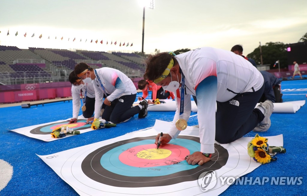 South Korean archers Oh Jin-hyek, Kim Je-deok and Kim Woo-jin (R to L) sign a commemorative target after winning the men's team gold medal at the Tokyo Olympics at Yumenoshima Park Archery Field in Tokyo on July 26, 2021. (Yonhap)