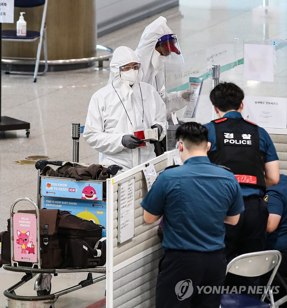 This Aug. 5, 2021, file photo shows migrant workers in full protective gear reporting to quarantine officials on arrival at Incheon International Airport, west of Seoul. (Yonhap)
