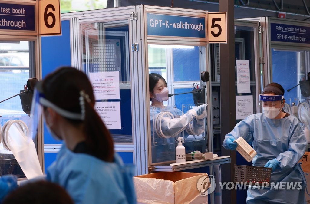 La foto, tomada el 15 de septiembre de 2021, muestra a trabajadores sanitarios, vestidos con trajes protectores, trabajando en una clínica provisional de exámenes de coronavirus, en Seúl.