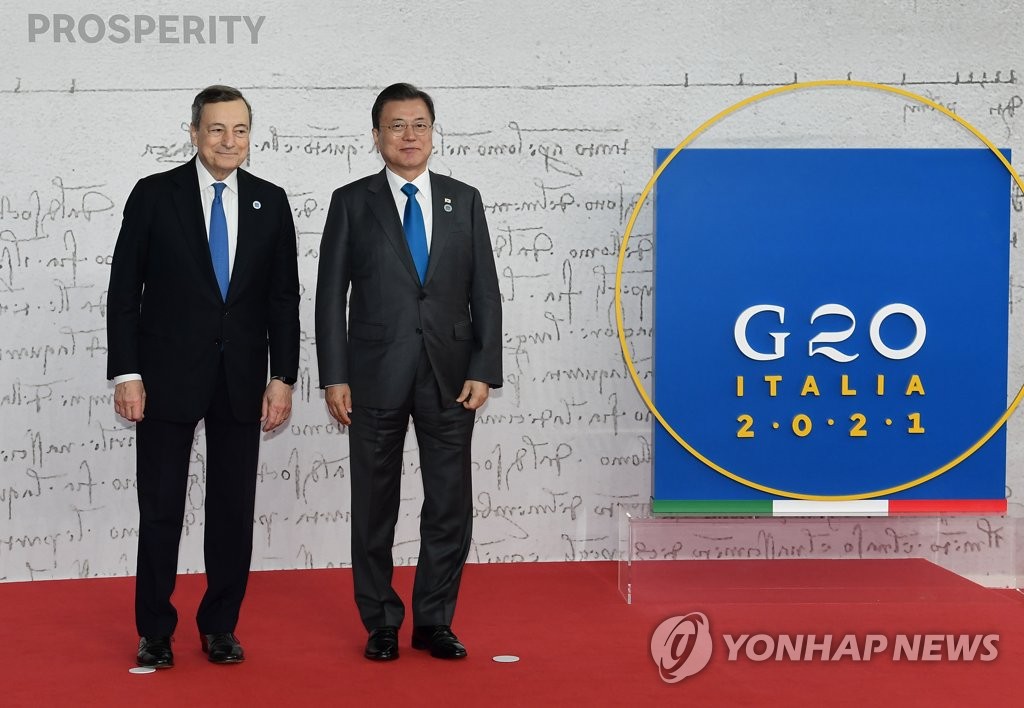 El presidente Moon Jae-in (dcha.) y el primer ministro italiano, Mario Draghi, anfitrión de la cumbre del G-20, posan para una foto antes de asistir, el 30 de octubre de 2021, a una ceremonia de bienvenida en Roma.
