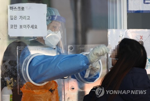 Un trabajador sanitario realiza una prueba de COVID-19 a una ciudadana, el 26 de noviembre de 2021, en una clínica provisional de pruebas instalada frente a la Estación de Seúl, en el centro de la capital.