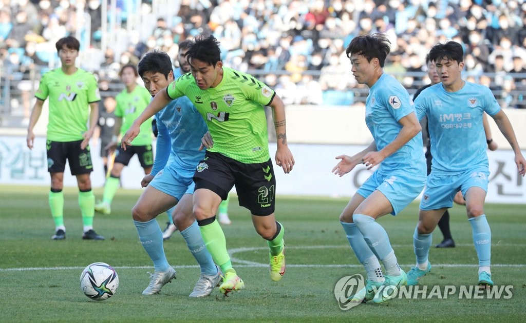 Song Min-kyu of Jeonbuk Hyundai Motors (C) and Lee Keun-ho of Daegu FC (L) battle for the ball during a K League 1 match at DGB Daegu Bank Park in Daegu, some 300 kilometers southeast of Seoul, on Nov. 28, 2021. (Yonhap)