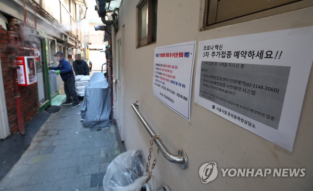 La foto, tomada el 27 de diciembre de 2021, muestra un aviso que alienta a recibir las vacunas de refuerzo contra el COVID-19, colocado en un barrio marginal, conocido como "jjokbangchon" en coreano, en el centro de Seúl.