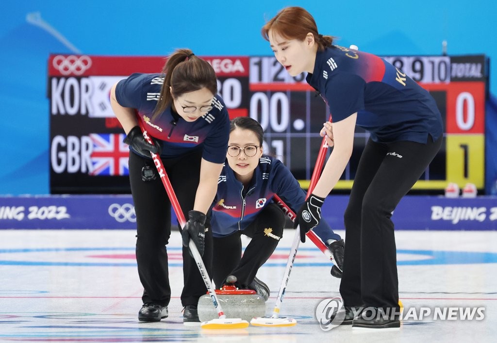 South Korean skip Kim Eun-jung (C) watches as her lead Kim Seon-yeong (L) and second Kim Cho-hi sweep the ice during the women's curling round robin game against Britain at the Beijing Winter Olympics at the National Aquatics Centre in Beijing on Feb. 11, 2022. (Yonhap)