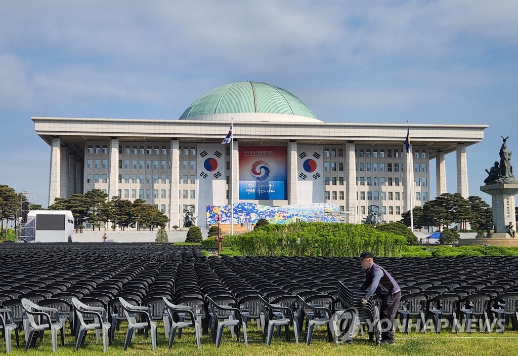 Des travailleurs installent des chaises pour les participants de la cérémonie d'investiture du 20e président de la République devant l'Assemblée nationale à Séoul, le vendredi 6 mai 2022. 