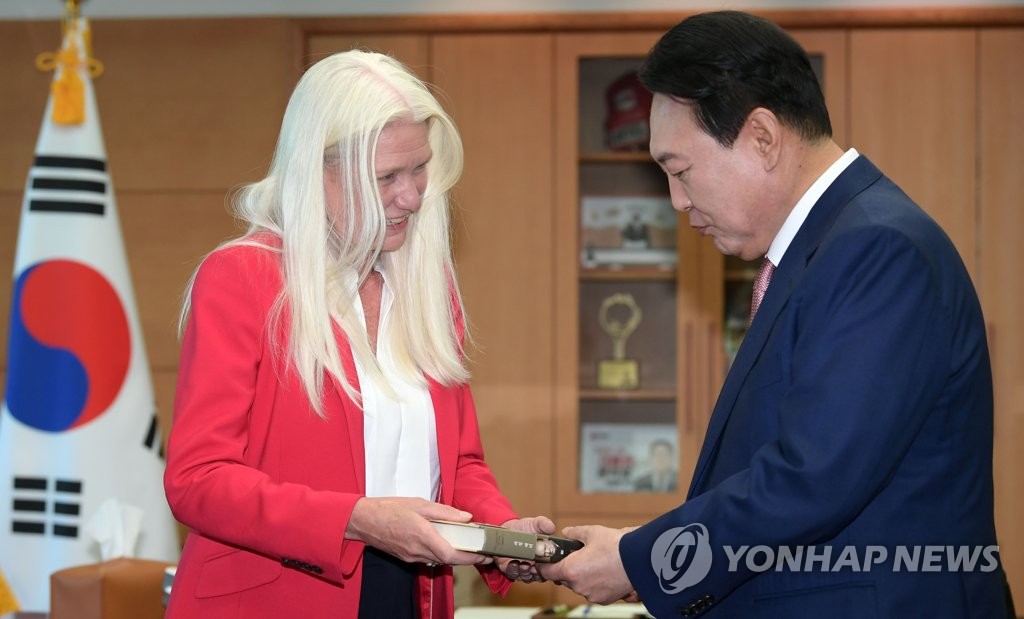 Amanda Milling (L), British minister of state for Asia and the Middle East, hands Prime Minister Boris Johnson's book "The Churchill Factor" to South Korean President-elect Yoon Suk-yeol during their meeting in Seoul on May 9, 2022. (Pool photo) (Yonhap)