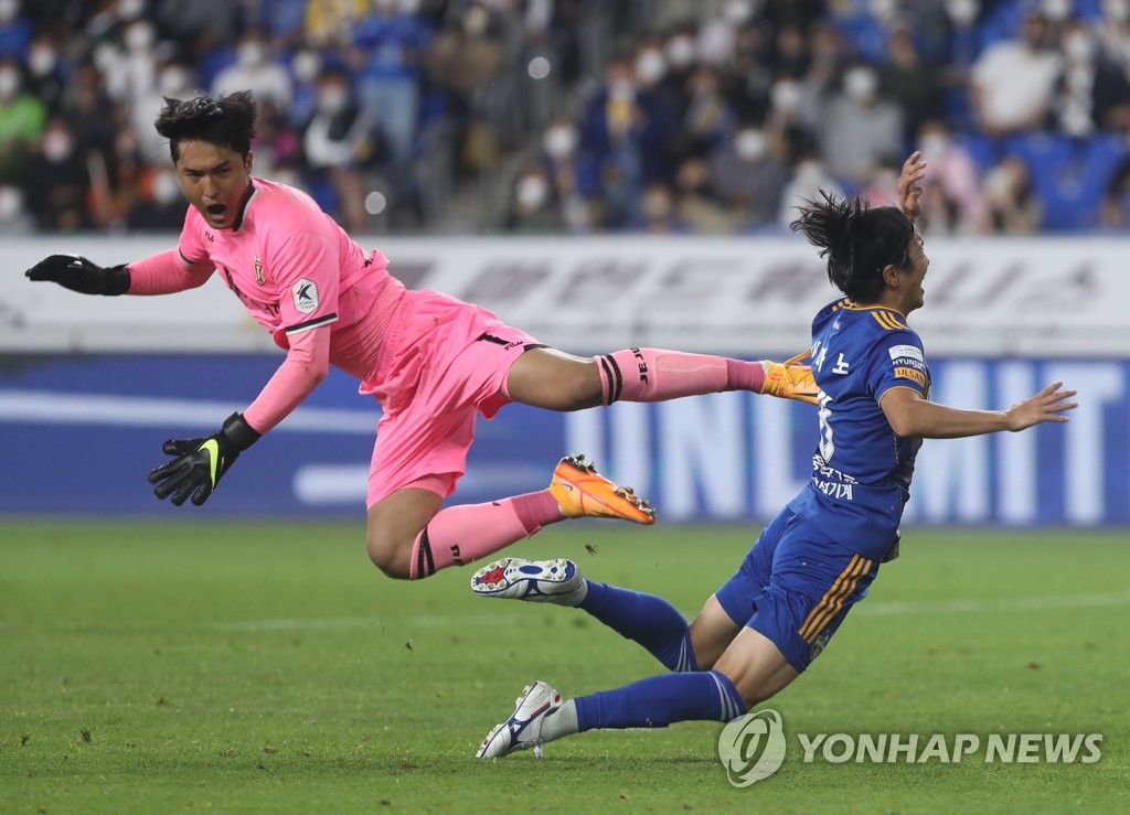Jun Amano of Ulsan Hyundai FC (R) falls after colliding with Jeju United goalkeeper Kim Dong-jun during the clubs' K League 1 match at Munsu Football Stadium in Ulsan, 415 kilometers southeast of Seoul, on May 18, 2022. (Yonhap)