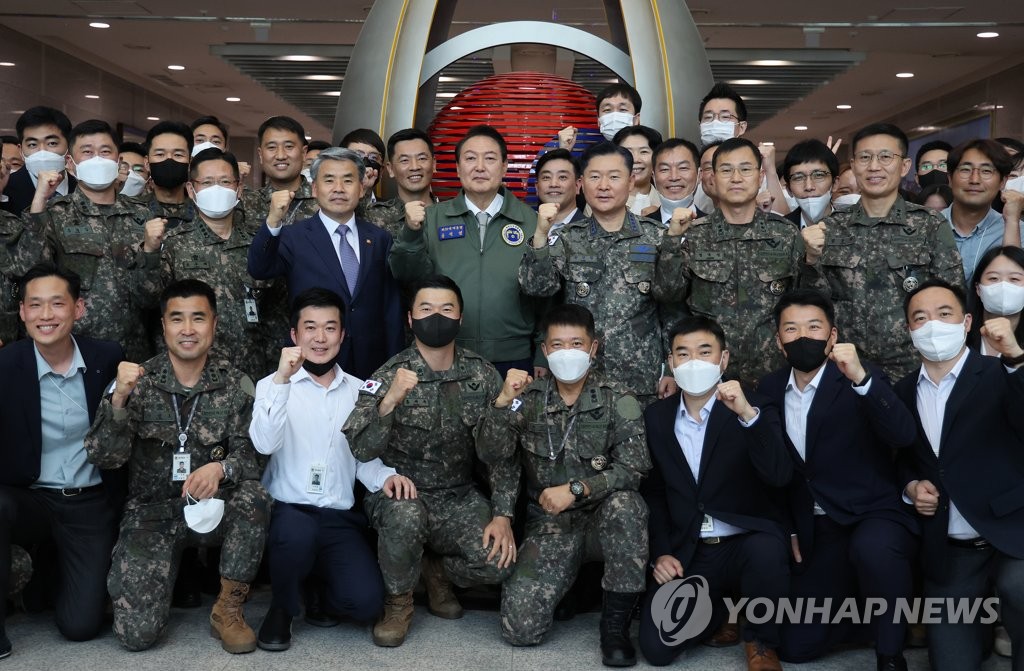 President Yoon Suk-yeol, wearing a bomber jacket, poses with Defense Minister Lee Jong-sup (to his right) and military officials during a visit to the office of the ministry and the Joint Chiefs of Staff in Yongsan, Seoul, on May 30, 2022. (Yonhap)