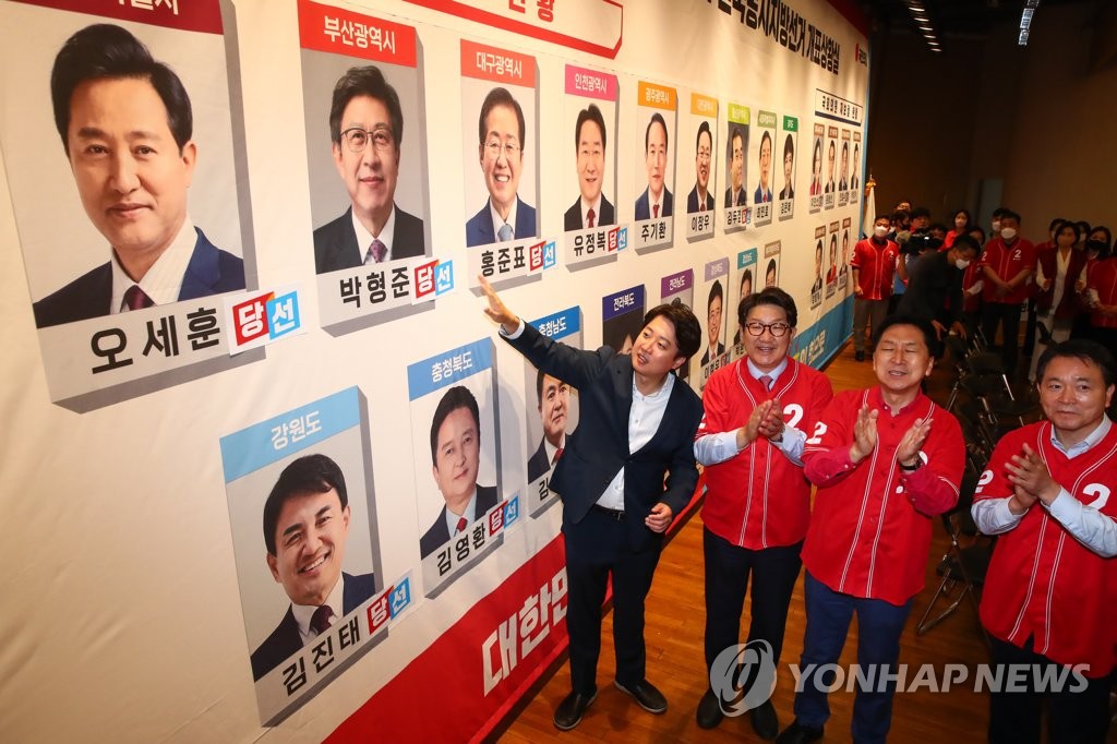 Leaders of the ruling People Power Party celebrate as they put stickers on the photos of candidates who are projected to win the local elections at the party's elections monitoring room at the National Assembly in Seoul on June 2, 2022. (Yonhap)