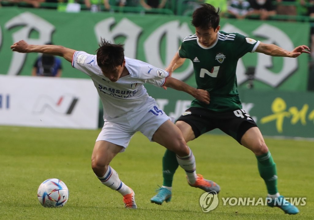 Kim Moon-hwan of Jeonbuk Hyundai Motors (R) and Jeon Jin-woo of Suwon Samsung Bluewings battle for the ball during the clubs' K League 1 match at Jeonju World Cup Stadium in Jeonju, 200 kilometers south of Seoul, on June 22, 2022. (Yonhap)