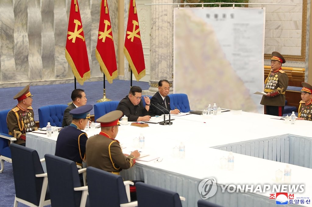 Ri Thae-sop (R), chief of the General Staff of the North's military, briefs North Korean leader Kim Jong-un (3rd from R, by the microphones), using a military map, during the second sitting of the third enlarged meeting of the eighth Central Military Commission of the ruling Workers' Party in Pyongyang on June 22, 2022, in this photo released by the official Korean Central News Agency the following day. (For Use Only in the Republic of Korea. No Redistribution) (Yonhap)