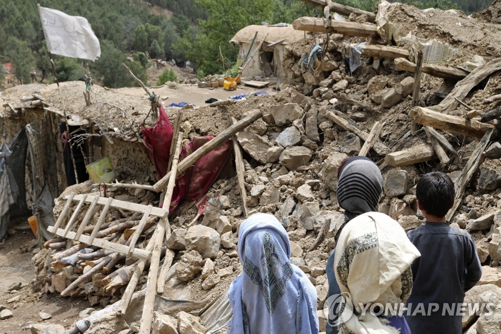 アフガニスタン東部のホストで、地震で倒壊した家屋と立ち尽くす人たち＝（ＡＰ＝聯合ニュース）