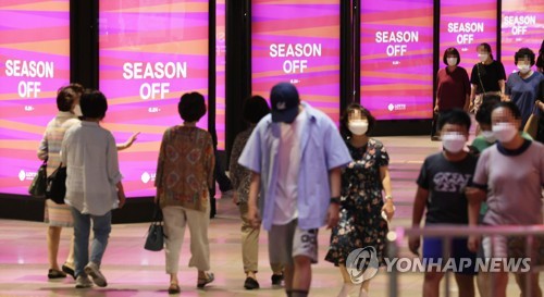 People walk past electronic display panels at a department store in Seoul on June 24, 2022. (Yonhap)